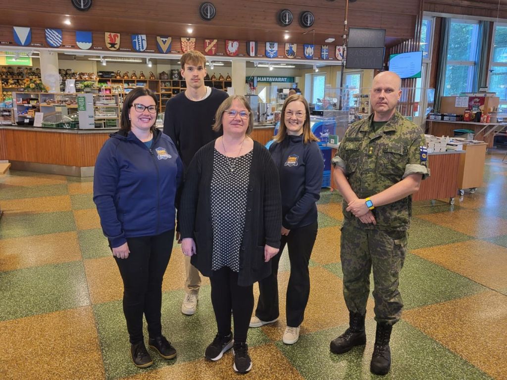 Asumiskokeilijaperhe, hanketyöntekijät ja varuskunnan edustaja poseeraavat sotilaskodissa